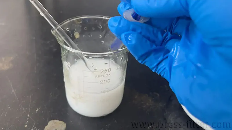 戴手套的操作人员在实验室烧杯中搅拌浅色聚合物分散液